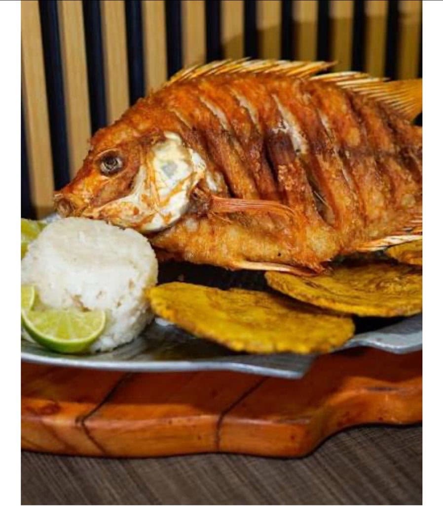 Whole fried mojarra with rice, tostones and lime